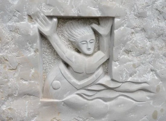 Relief in hellem Naturstein: eine Figur mit erhobenen Armen unter einer Deckplatte